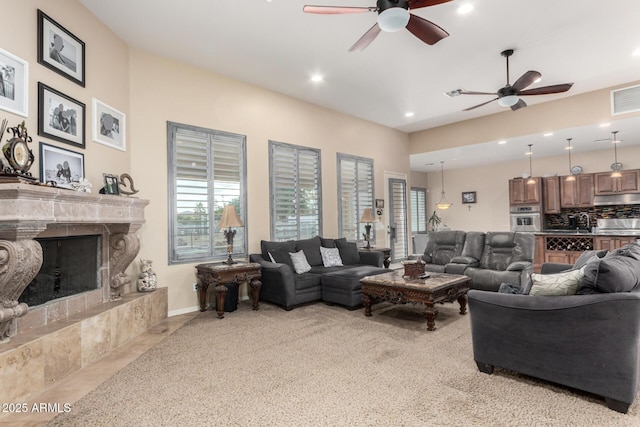 carpeted living room with ceiling fan and a fireplace