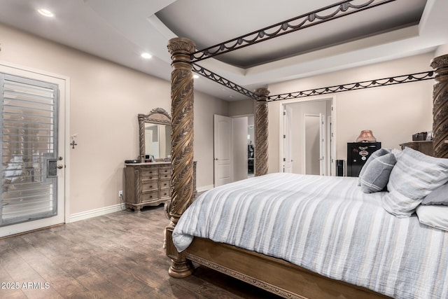 bedroom featuring a tray ceiling, hardwood / wood-style floors, and access to exterior