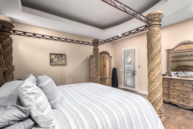 bedroom featuring dark hardwood / wood-style floors, access to exterior, and a tray ceiling