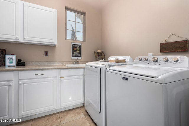 clothes washing area with sink, light tile patterned floors, washer and clothes dryer, and cabinets