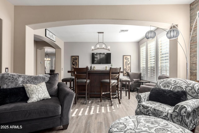 living room featuring hardwood / wood-style floors, a chandelier, and bar area