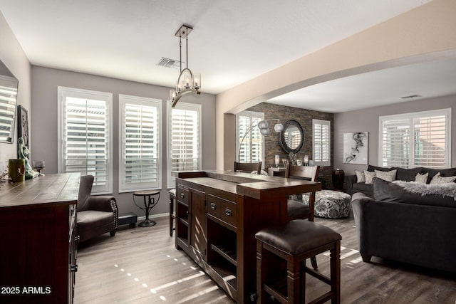 kitchen with dark brown cabinets, light hardwood / wood-style flooring, tile counters, a chandelier, and hanging light fixtures