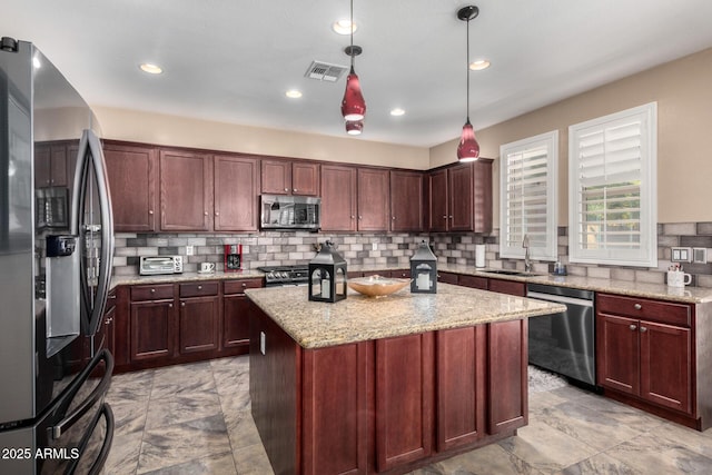 kitchen featuring appliances with stainless steel finishes, a kitchen island, pendant lighting, and sink