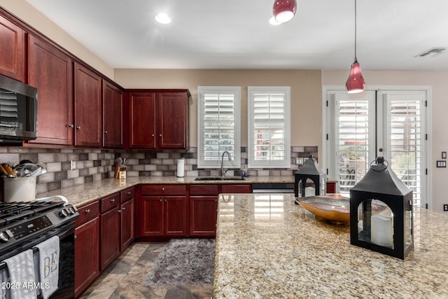 kitchen with gas range oven, tasteful backsplash, light stone counters, and sink