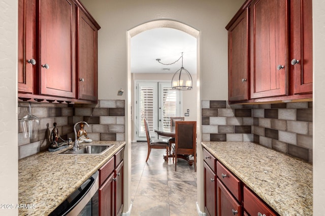 kitchen featuring decorative light fixtures, tasteful backsplash, light stone counters, and sink