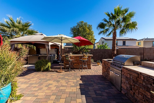 view of patio / terrace featuring a gazebo, area for grilling, a grill, and exterior bar