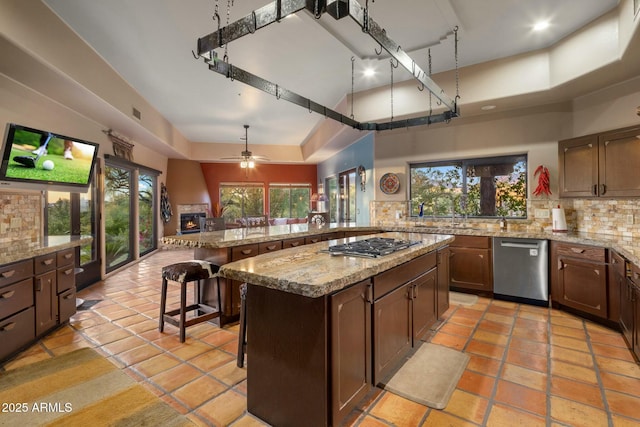 kitchen with a breakfast bar, decorative backsplash, a center island, stainless steel appliances, and a healthy amount of sunlight