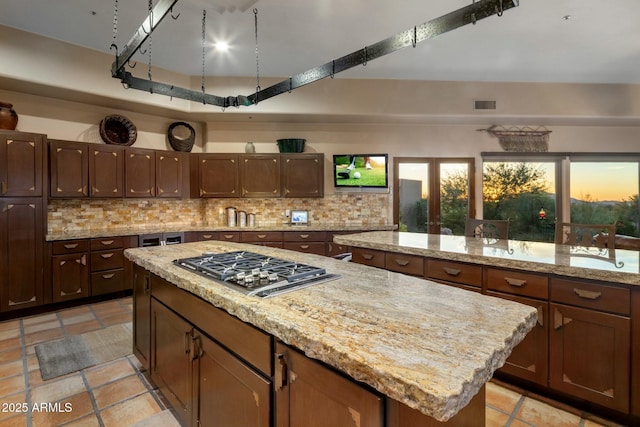 kitchen featuring sink, decorative backsplash, a center island, and stainless steel gas cooktop