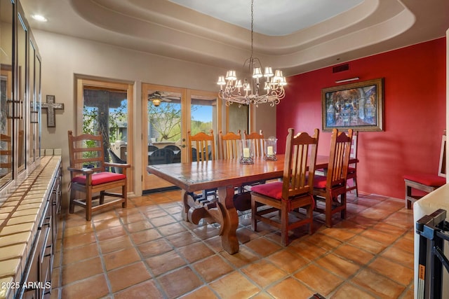 dining area featuring an inviting chandelier, a raised ceiling, and french doors