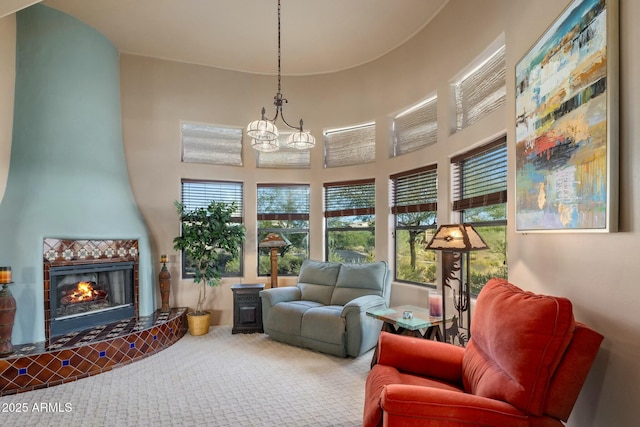 sitting room with an inviting chandelier, a wood stove, carpet floors, a towering ceiling, and a fireplace