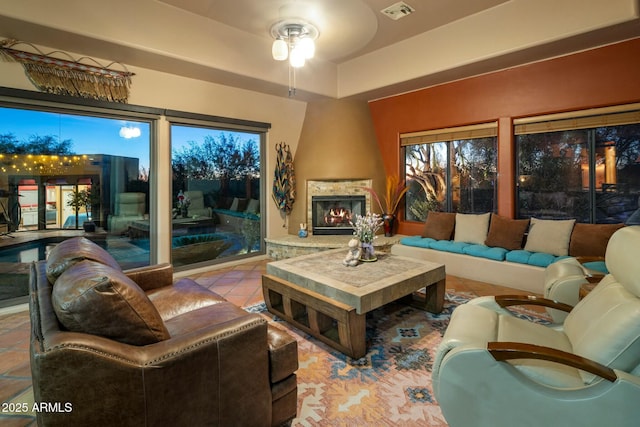 living room featuring a large fireplace, ceiling fan, and light tile patterned flooring