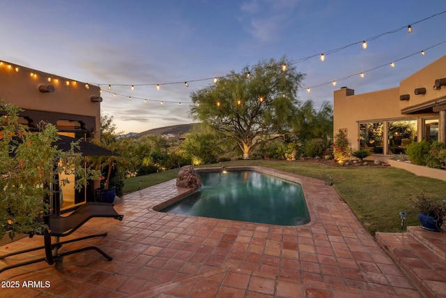 pool at dusk featuring a yard and a patio