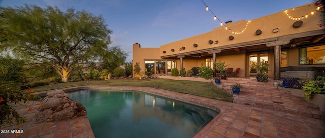 pool at dusk featuring a patio area