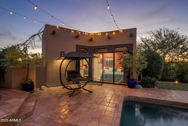 back house at dusk featuring a patio area