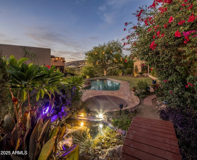 pool at dusk with a patio area