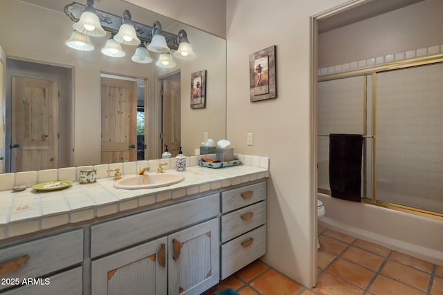 full bathroom featuring vanity, bath / shower combo with glass door, tile patterned floors, and toilet