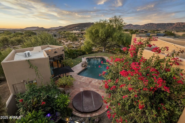 pool at dusk with a mountain view and a patio area