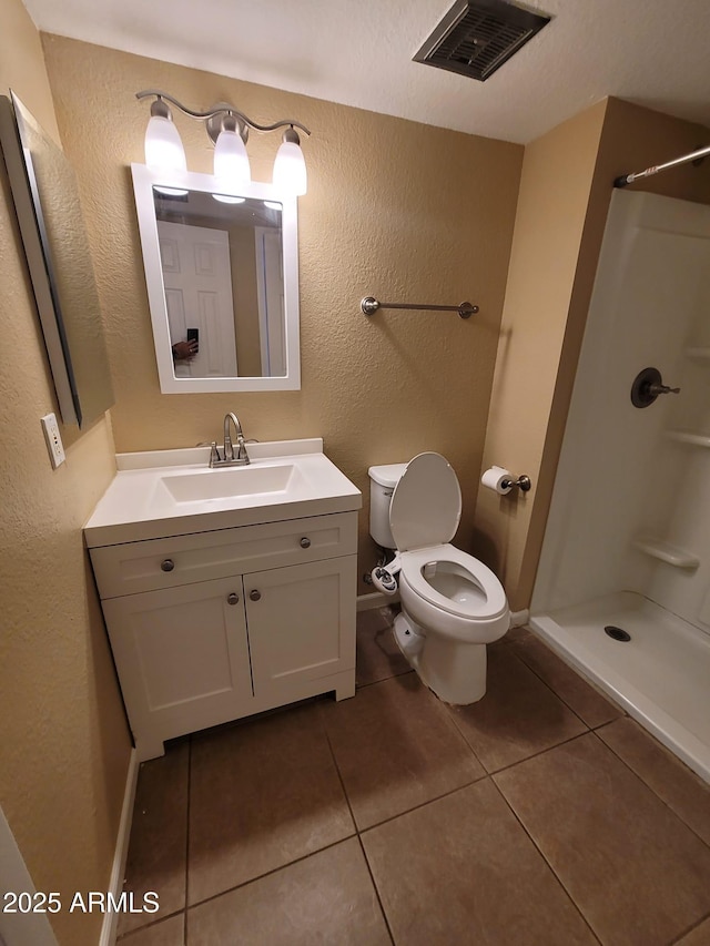 bathroom featuring vanity, a shower, tile patterned floors, and toilet