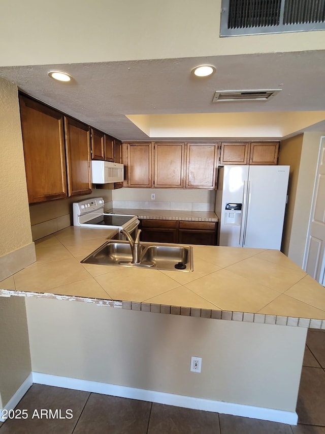 kitchen with sink, white appliances, tile patterned flooring, tile countertops, and kitchen peninsula