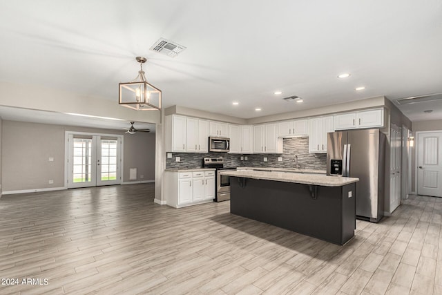 kitchen with stainless steel appliances, decorative light fixtures, decorative backsplash, and white cabinets