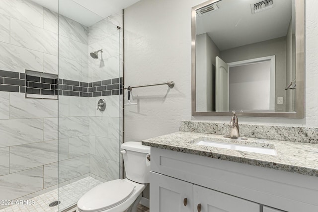 bathroom featuring vanity, toilet, and tiled shower