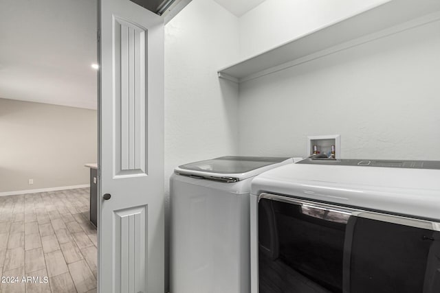 laundry room with light hardwood / wood-style floors and washing machine and clothes dryer