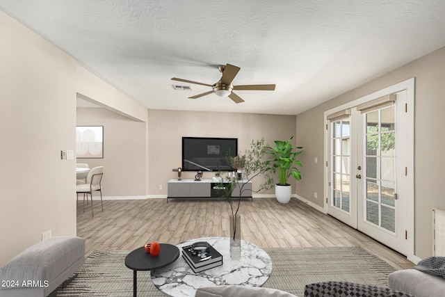 living room with ceiling fan, light hardwood / wood-style flooring, french doors, and a textured ceiling