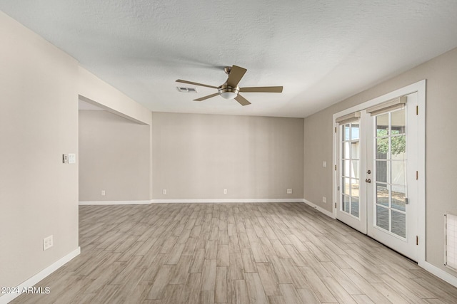 empty room featuring french doors, ceiling fan, a textured ceiling, and light wood-type flooring