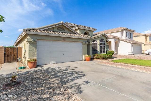 3418 W Maldonado Rd, Phoenix, AZ 85041 - mediterranean / spanish-style house featuring a garage, stucco siding, concrete driveway, a tile roof, and a gate