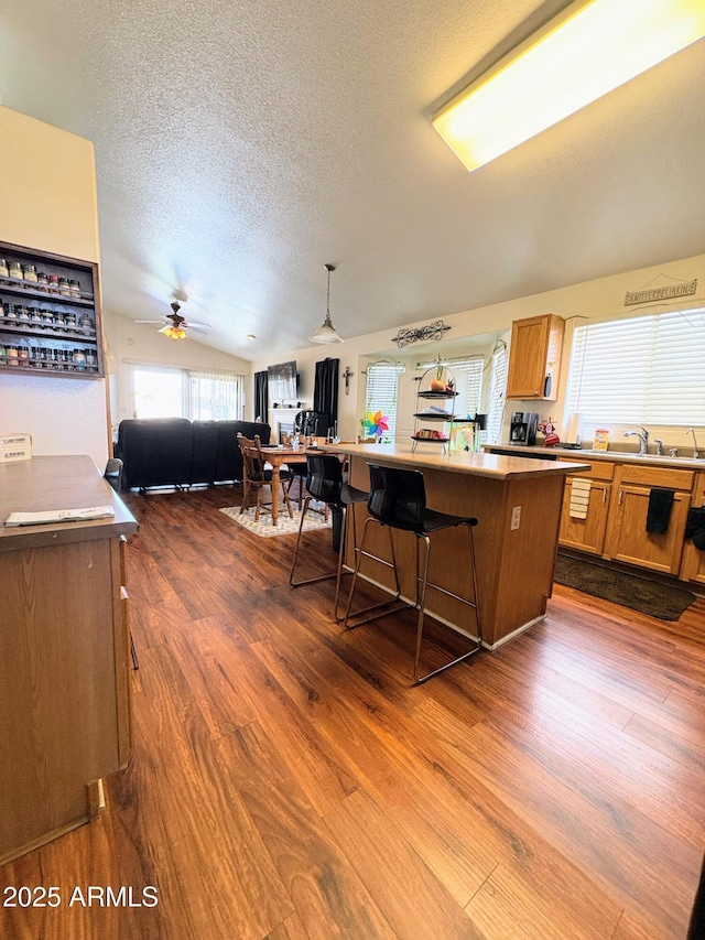 3418 W Maldonado Rd, Phoenix, AZ 85041 - kitchen featuring vaulted ceiling, a center island, brown cabinets, a textured ceiling, and dark wood finished floors