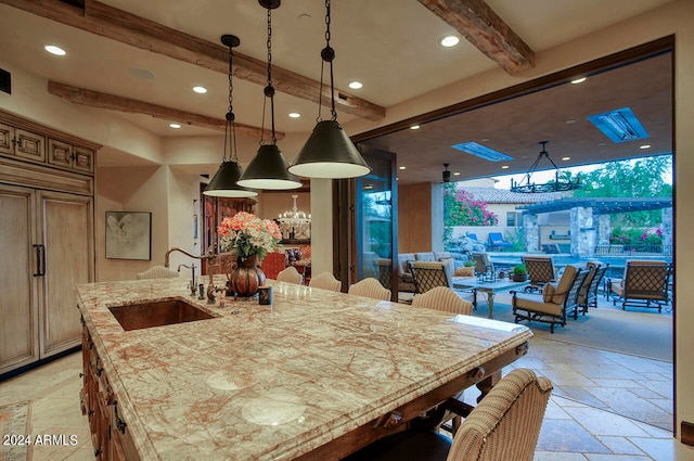 dining space with beam ceiling, sink, and a notable chandelier