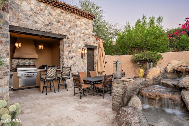 patio terrace at dusk with an outdoor kitchen and grilling area