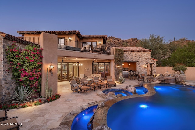 pool at dusk with an in ground hot tub, a patio area, and pool water feature