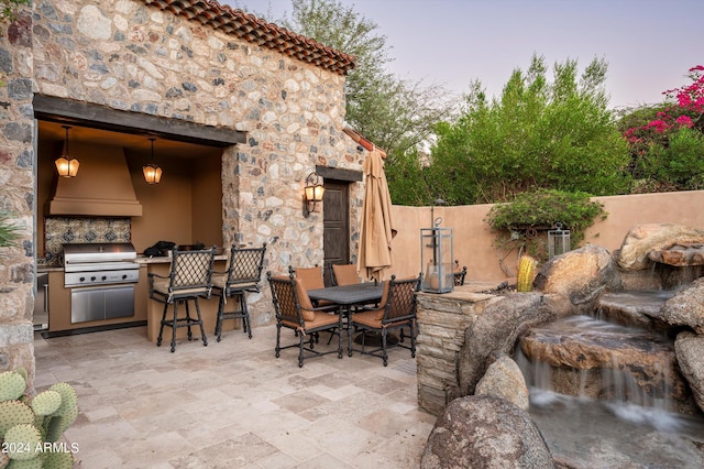 view of patio / terrace with exterior kitchen, outdoor dining space, and a grill