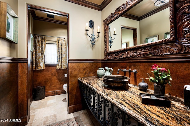 full bathroom with vanity, a wainscoted wall, stone finish flooring, toilet, and ornamental molding