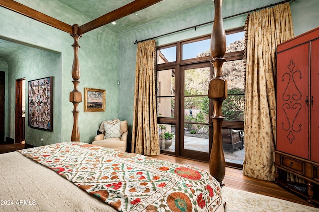 bedroom with wood finished floors, beam ceiling, and access to outside