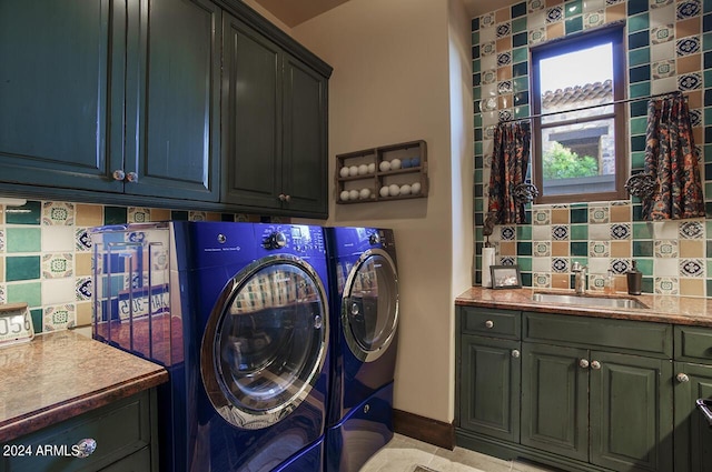 washroom featuring cabinet space, washing machine and dryer, baseboards, and a sink