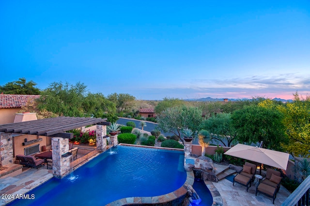 pool at dusk with a patio area and pool water feature