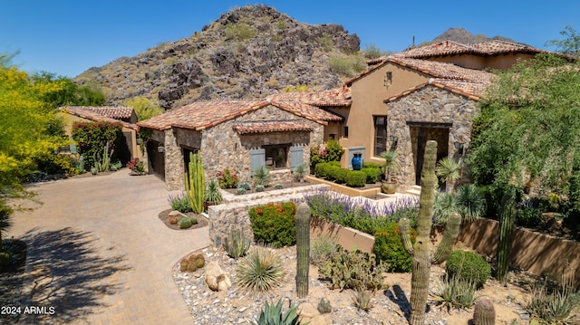 mediterranean / spanish house with a mountain view, driveway, stone siding, an attached garage, and stucco siding