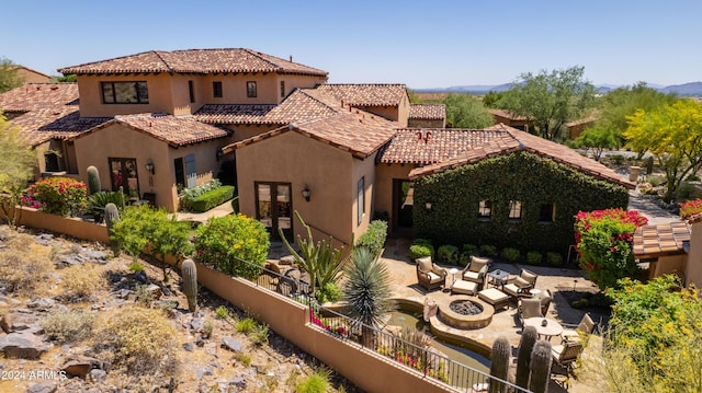 back of house with stucco siding, french doors, a tile roof, and an outdoor fire pit