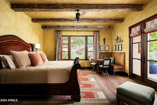 bedroom featuring beam ceiling, wood-type flooring, multiple windows, and ceiling fan