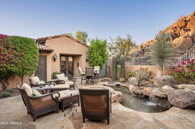view of patio / terrace with fence, french doors, and a garden pond