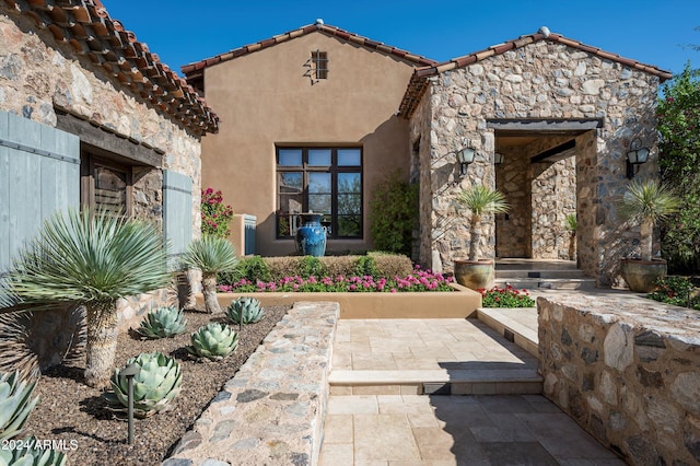 property entrance featuring stone siding, a tiled roof, and stucco siding