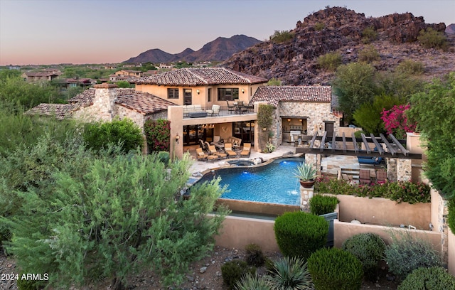 pool at dusk featuring a patio and a mountain view