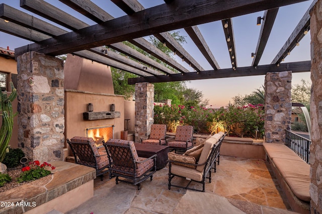 patio terrace at dusk featuring an outdoor living space with a fireplace and a pergola