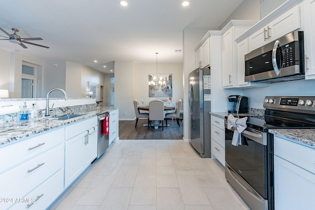 kitchen featuring white cabinetry, light stone countertops, sink, pendant lighting, and stainless steel appliances