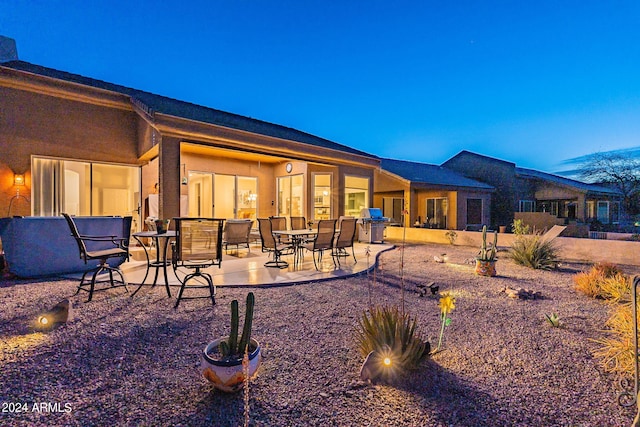 back house at dusk with a patio