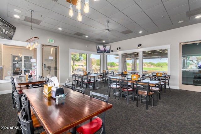 dining area featuring a drop ceiling and dark colored carpet