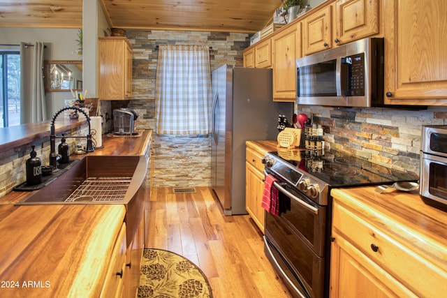 kitchen with backsplash, butcher block counters, wooden ceiling, and stainless steel appliances