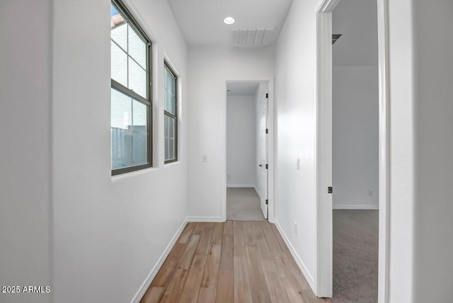 corridor with visible vents, baseboards, and wood finished floors